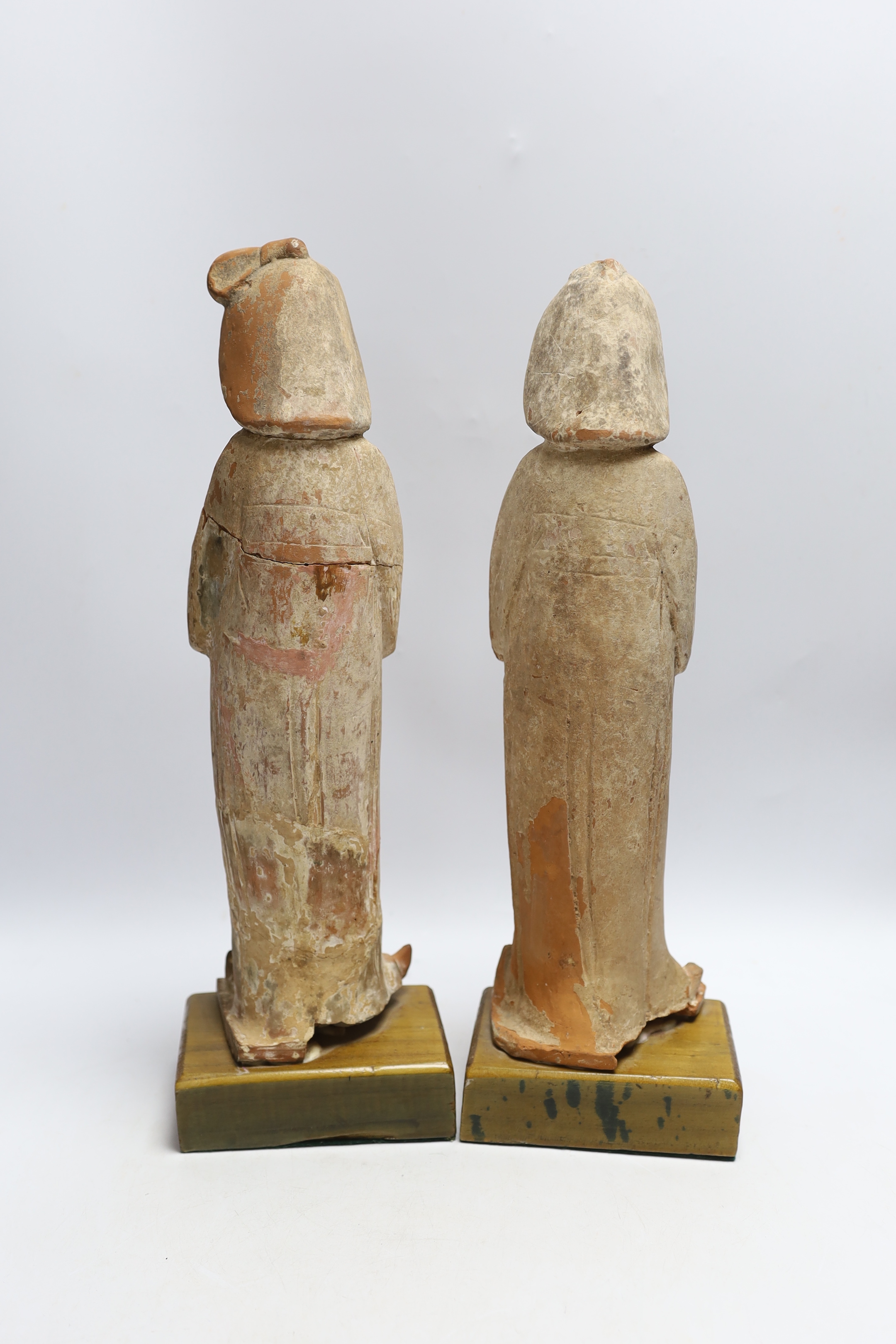 A pair of Chinese painted terracotta figures, possibly Tang Dynasty, on stained pine bases, 42cm high
